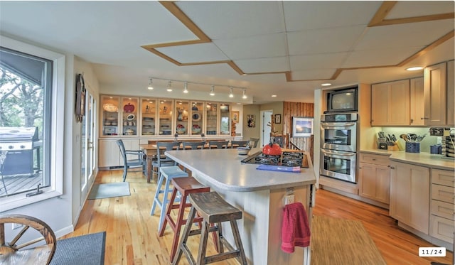 kitchen featuring a center island, a kitchen bar, light countertops, light wood-style flooring, and stainless steel appliances