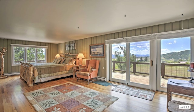 bedroom featuring light wood-type flooring, access to exterior, a mountain view, and a baseboard radiator