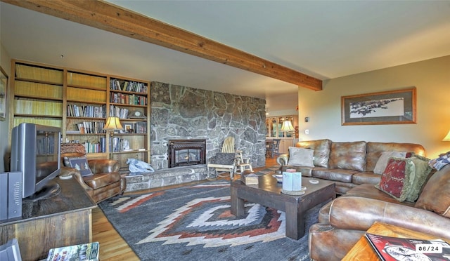 living room with a fireplace, beam ceiling, and wood finished floors