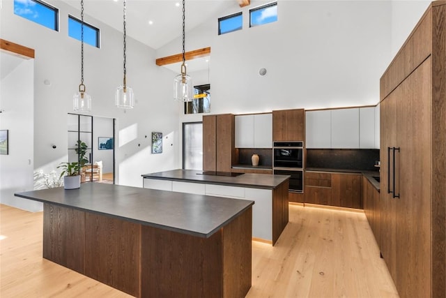 kitchen with white cabinetry, a center island, hanging light fixtures, high vaulted ceiling, and backsplash