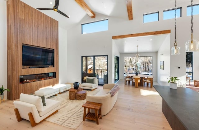 living room with a fireplace, a high ceiling, light wood-type flooring, and ceiling fan