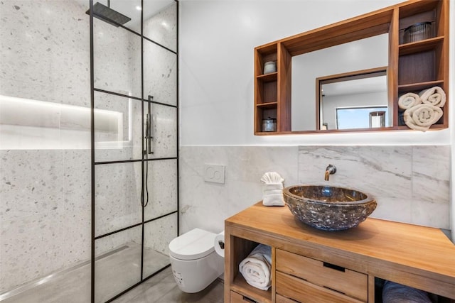 bathroom with a tile shower, vanity, toilet, and backsplash