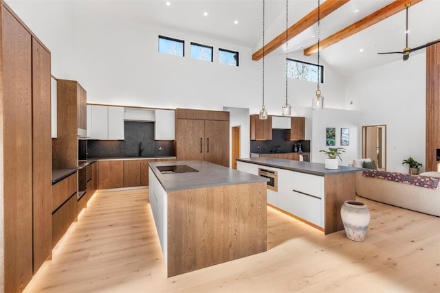 kitchen featuring beam ceiling, hanging light fixtures, a kitchen island, high vaulted ceiling, and white cabinets