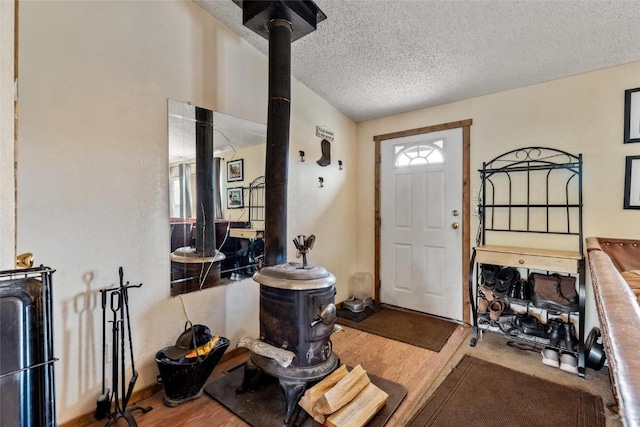 foyer entrance with hardwood / wood-style floors, a healthy amount of sunlight, a wood stove, and a textured ceiling