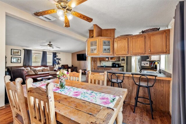 dining room with beamed ceiling, light hardwood / wood-style floors, sink, and a textured ceiling