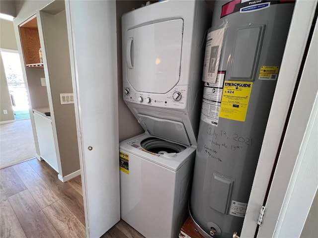 laundry room with water heater, light hardwood / wood-style flooring, and stacked washing maching and dryer