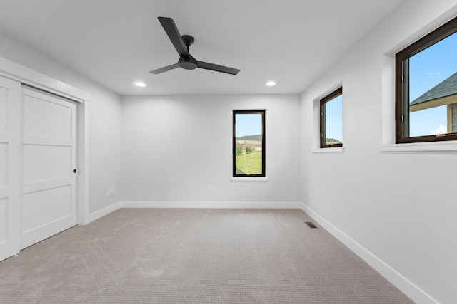 unfurnished bedroom featuring multiple windows, ceiling fan, and light colored carpet