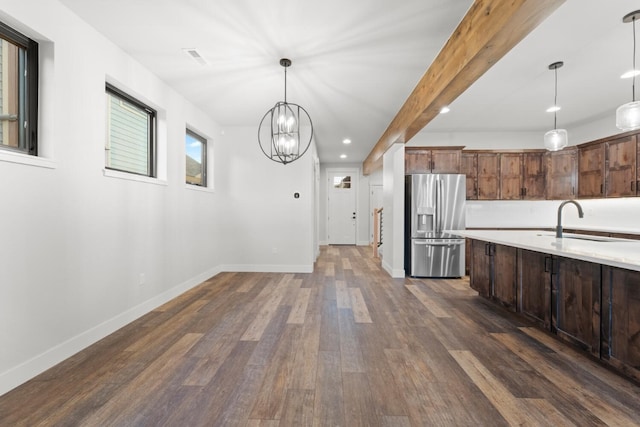 kitchen featuring dark wood-type flooring, sink, stainless steel refrigerator with ice dispenser, hanging light fixtures, and beamed ceiling