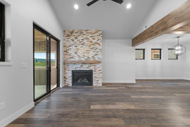 unfurnished living room with a stone fireplace, ceiling fan with notable chandelier, dark wood-type flooring, and lofted ceiling