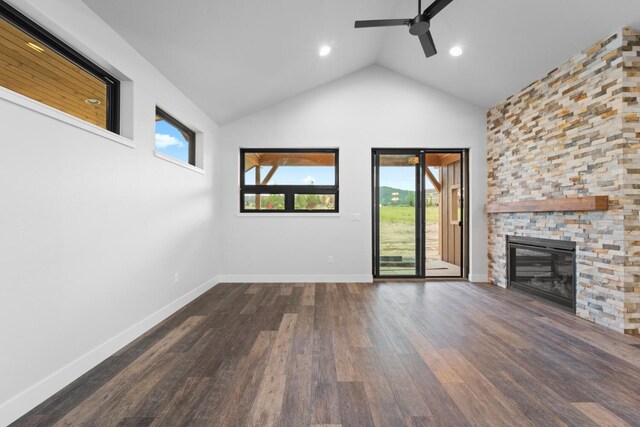 unfurnished living room featuring a stone fireplace, ceiling fan, dark hardwood / wood-style flooring, and high vaulted ceiling