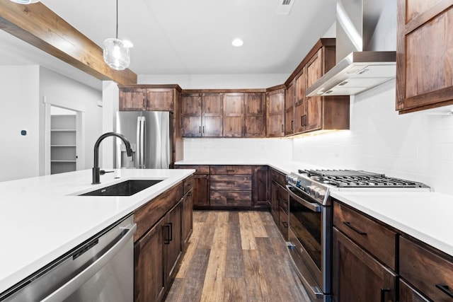 kitchen featuring pendant lighting, sink, wall chimney exhaust hood, dark hardwood / wood-style floors, and stainless steel appliances