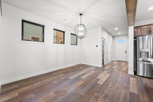 unfurnished dining area featuring a notable chandelier and dark hardwood / wood-style flooring