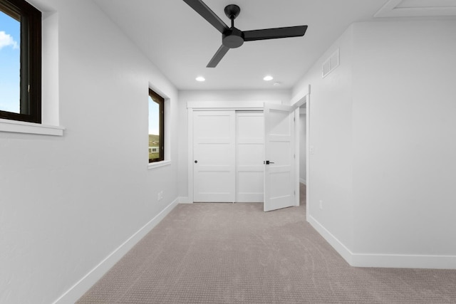 unfurnished bedroom with a closet, light colored carpet, and ceiling fan