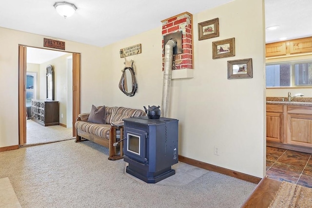 living room with a wood stove, sink, and dark colored carpet