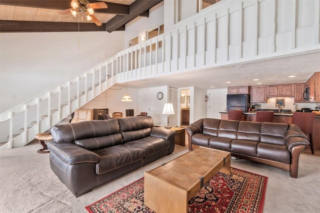 living room with beamed ceiling, a towering ceiling, and light carpet