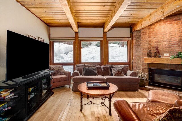 living room with light wood-type flooring, beam ceiling, wood ceiling, brick wall, and a brick fireplace