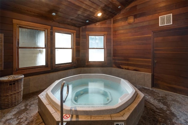 bathroom featuring visible vents, wood walls, wood ceiling, lofted ceiling, and a whirlpool tub