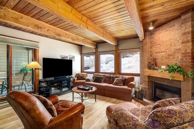 living room featuring beamed ceiling, a fireplace, wood ceiling, and light wood-type flooring