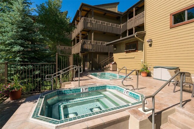 view of swimming pool with a patio area, fence, and a hot tub