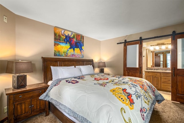 bedroom with a barn door, carpet, and connected bathroom