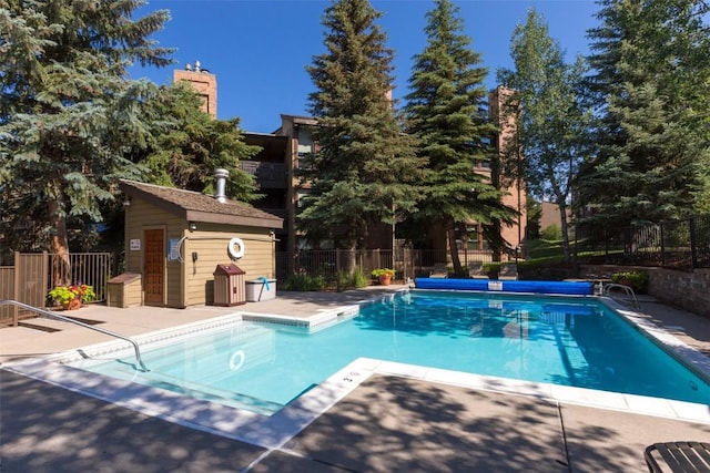 view of pool featuring a fenced in pool, a patio, an outdoor structure, and fence