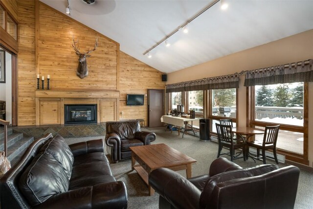 carpeted living area with a glass covered fireplace, wood walls, rail lighting, and high vaulted ceiling