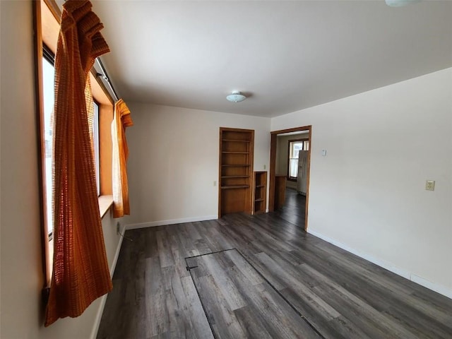 unfurnished bedroom with dark wood-type flooring and stainless steel fridge