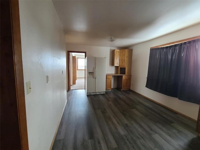 unfurnished living room featuring built in desk and dark hardwood / wood-style flooring