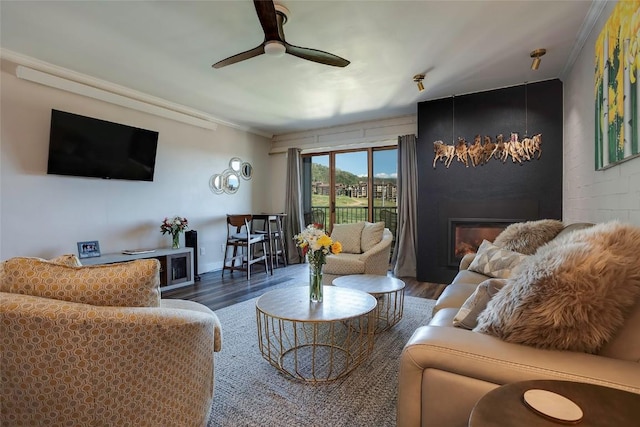 living room featuring dark hardwood / wood-style floors, a large fireplace, crown molding, and ceiling fan