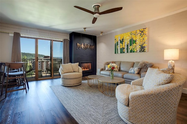 living room with ceiling fan, a fireplace, dark wood-type flooring, and ornamental molding