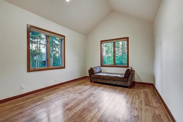 living area with light hardwood / wood-style floors, lofted ceiling, and a wealth of natural light