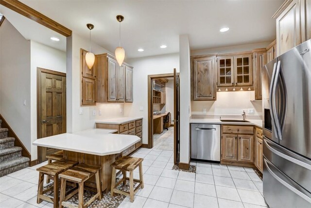 kitchen with appliances with stainless steel finishes, a breakfast bar, sink, light tile patterned floors, and hanging light fixtures