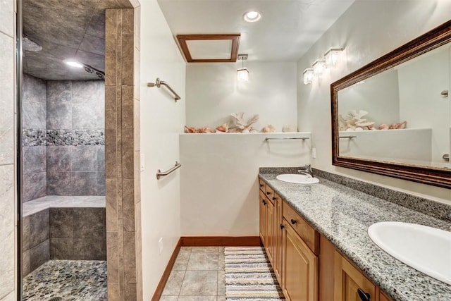 bathroom with a tile shower, vanity, and tile patterned floors