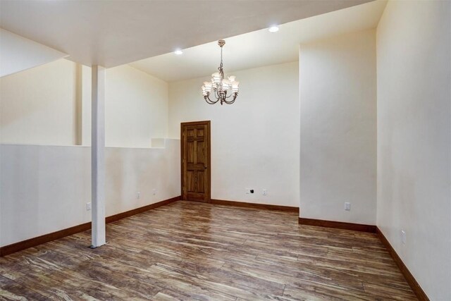 unfurnished room featuring a chandelier and dark wood-type flooring