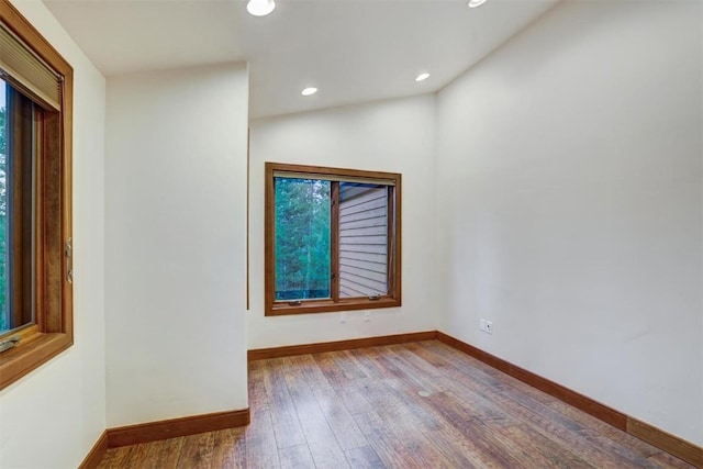 unfurnished room with hardwood / wood-style flooring, a healthy amount of sunlight, and lofted ceiling