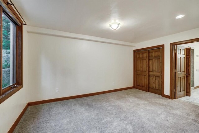 unfurnished bedroom with light colored carpet and a closet