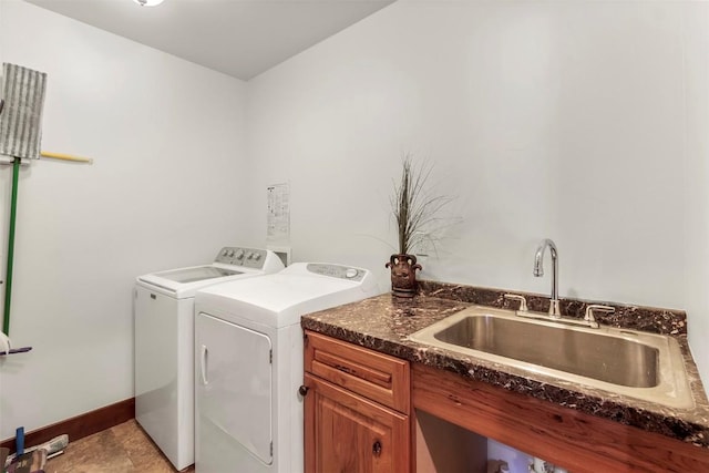 laundry area featuring baseboards, washer and dryer, and a sink