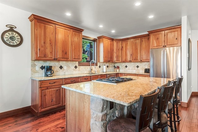 kitchen with stainless steel appliances, light stone countertops, a sink, and dark wood-style floors