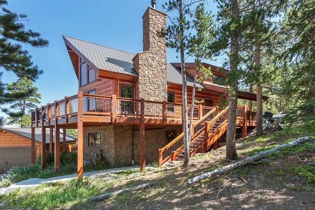 rear view of house featuring a chimney, stairway, a standing seam roof, metal roof, and stone siding