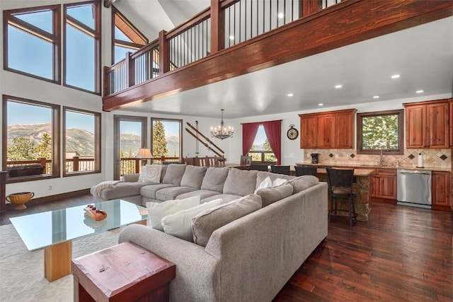 living area with dark wood-style floors, recessed lighting, a notable chandelier, and a high ceiling