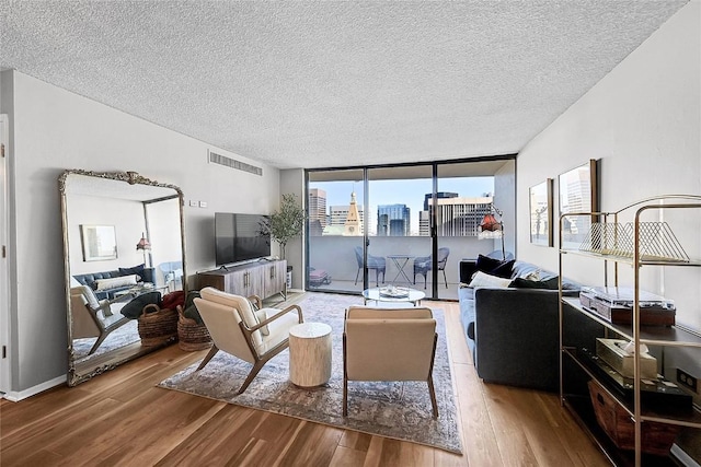 living room with hardwood / wood-style floors, a wall of windows, and a textured ceiling