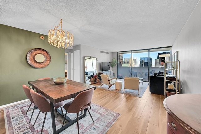 dining room featuring a chandelier, a textured ceiling, and light wood-type flooring