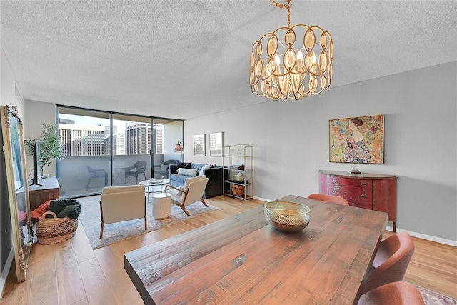 dining area featuring expansive windows, a textured ceiling, a notable chandelier, and light wood-type flooring