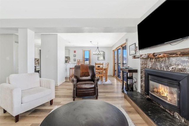 living room featuring light hardwood / wood-style floors, a high end fireplace, and a chandelier