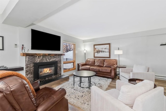 living room with a baseboard heating unit, a fireplace, and light wood-type flooring