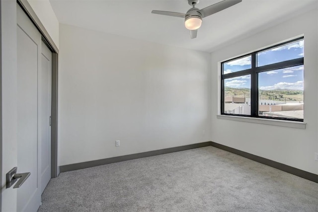 unfurnished bedroom with ceiling fan, a closet, and light carpet