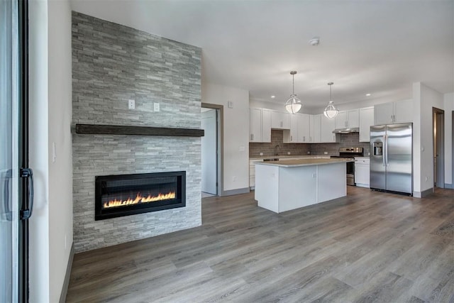 kitchen featuring a center island, decorative light fixtures, light hardwood / wood-style floors, white cabinetry, and stainless steel appliances