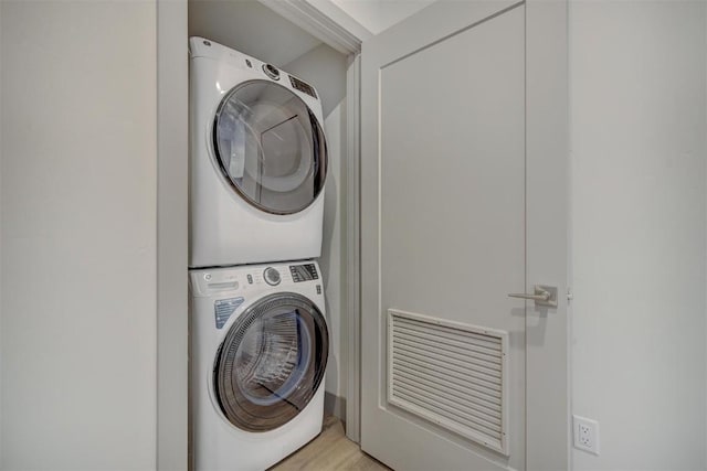 laundry room with light wood-type flooring and stacked washing maching and dryer