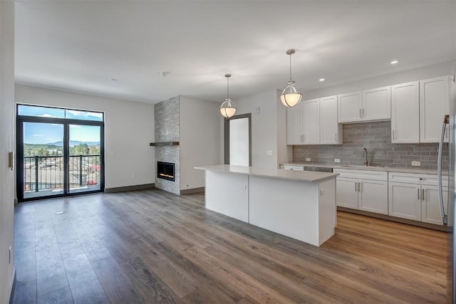 kitchen featuring decorative light fixtures, a center island, white cabinetry, and sink