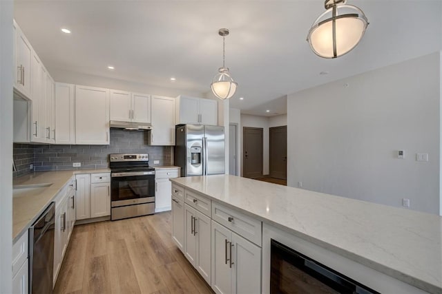 kitchen with light stone countertops, appliances with stainless steel finishes, backsplash, white cabinetry, and hanging light fixtures